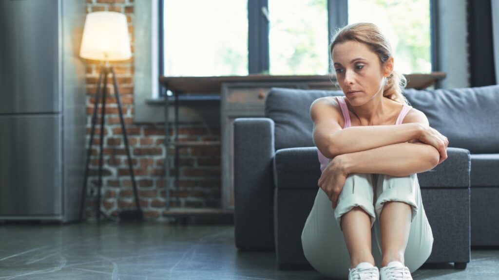 Woman sitting on floor looking sad and confused